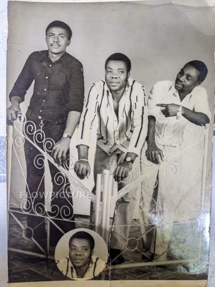 Three men leaning on a wrought-iron gate, from black and white to colour
